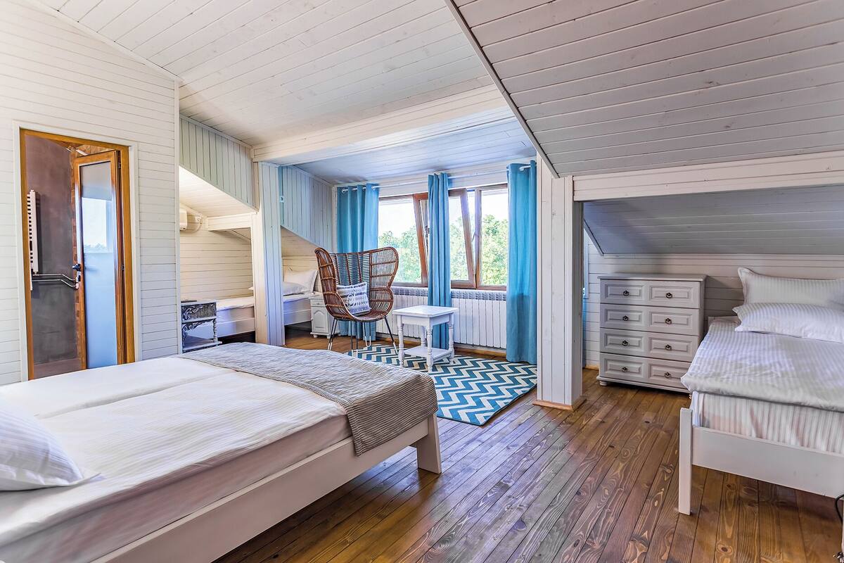 A bedroom with two beds, a chair, a small table, and a dresser.