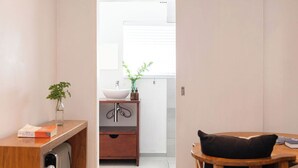 Een moderne badkamer met een houten wastafelmeubel, een witte wasbak en een kleine plant.