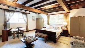 Een slaapkamer met een houten plafond, een bed, nachtkastje, stoel, bureau en een kledingkast.