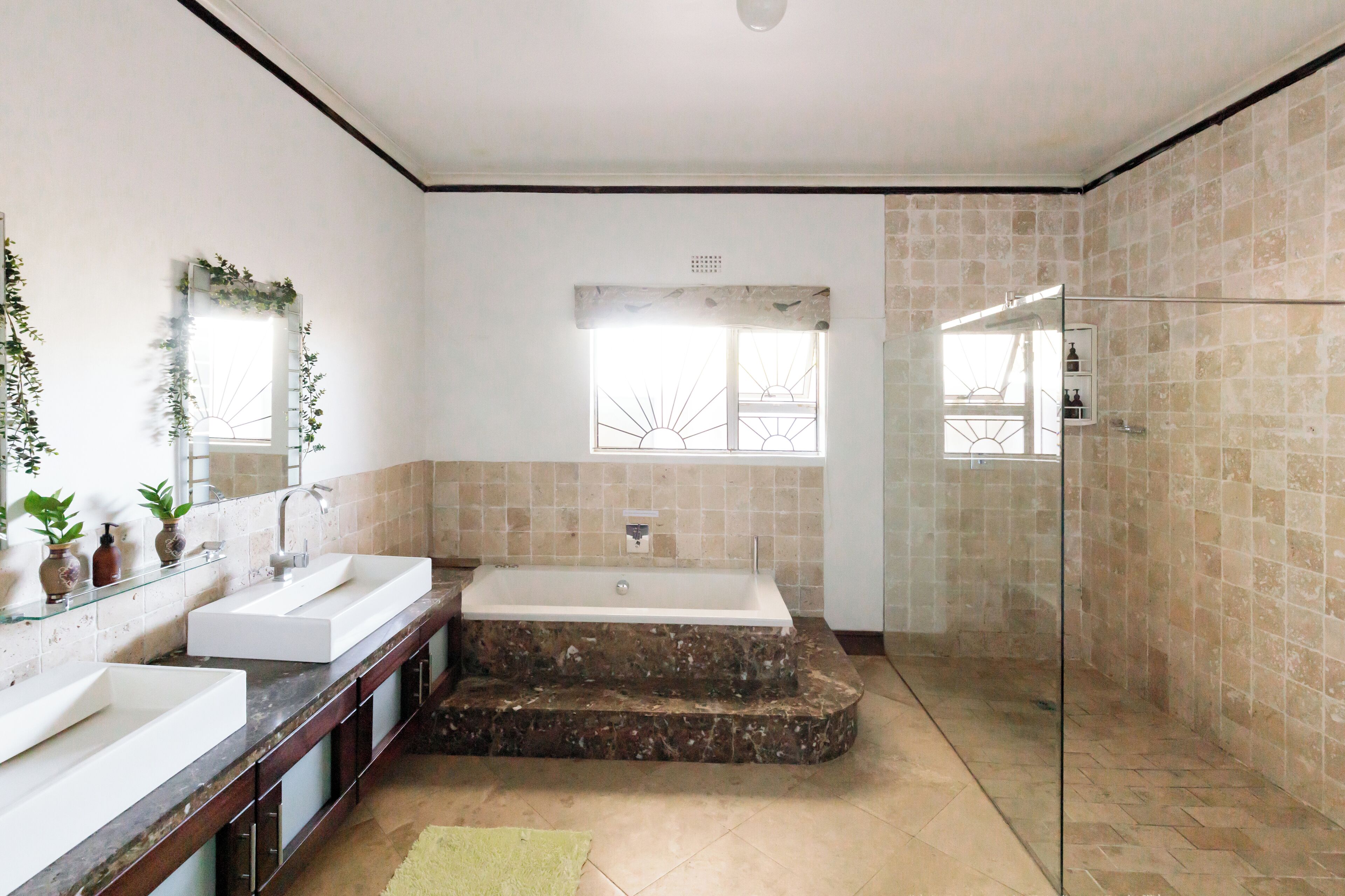 A modern bathroom with a large bathtub, two sinks, and a glass shower enclosure.
