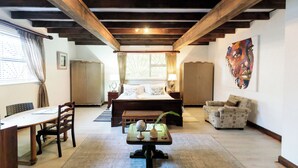 A bedroom with a large bed, a desk with a globe, a chair, a sofa, and a painting on the wall. - Staymore Guesthouse (Stellenbosch)