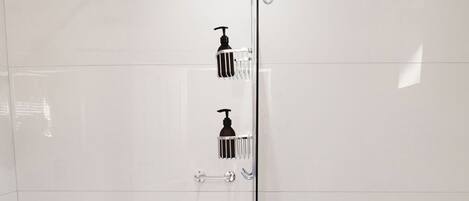 A modern bathroom with a glass-enclosed shower, a toilet, and a potted plant.