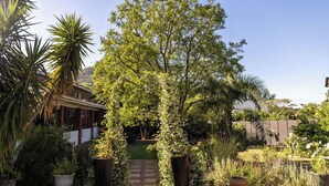 Een tuin met diverse planten en een pad dat naar een huis leidt.