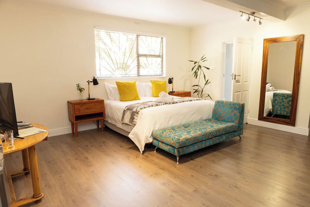 A bedroom with a bed, bedside tables, a desk, a chair, a mirror, and a window.