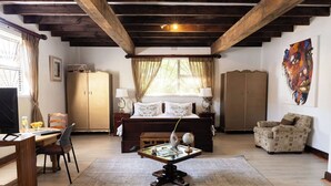 Een slaapkamer met een groot bed, een bureau, een stoel, een bank en een schilderij aan de muur.
