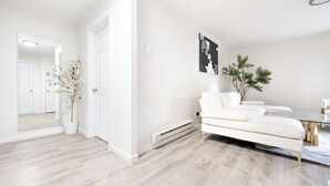 A modern living room with a white sofa, a glass coffee table, and a potted plant. - Ultra-Modern Luxe Sleek & Stunning Stay (White Plains)