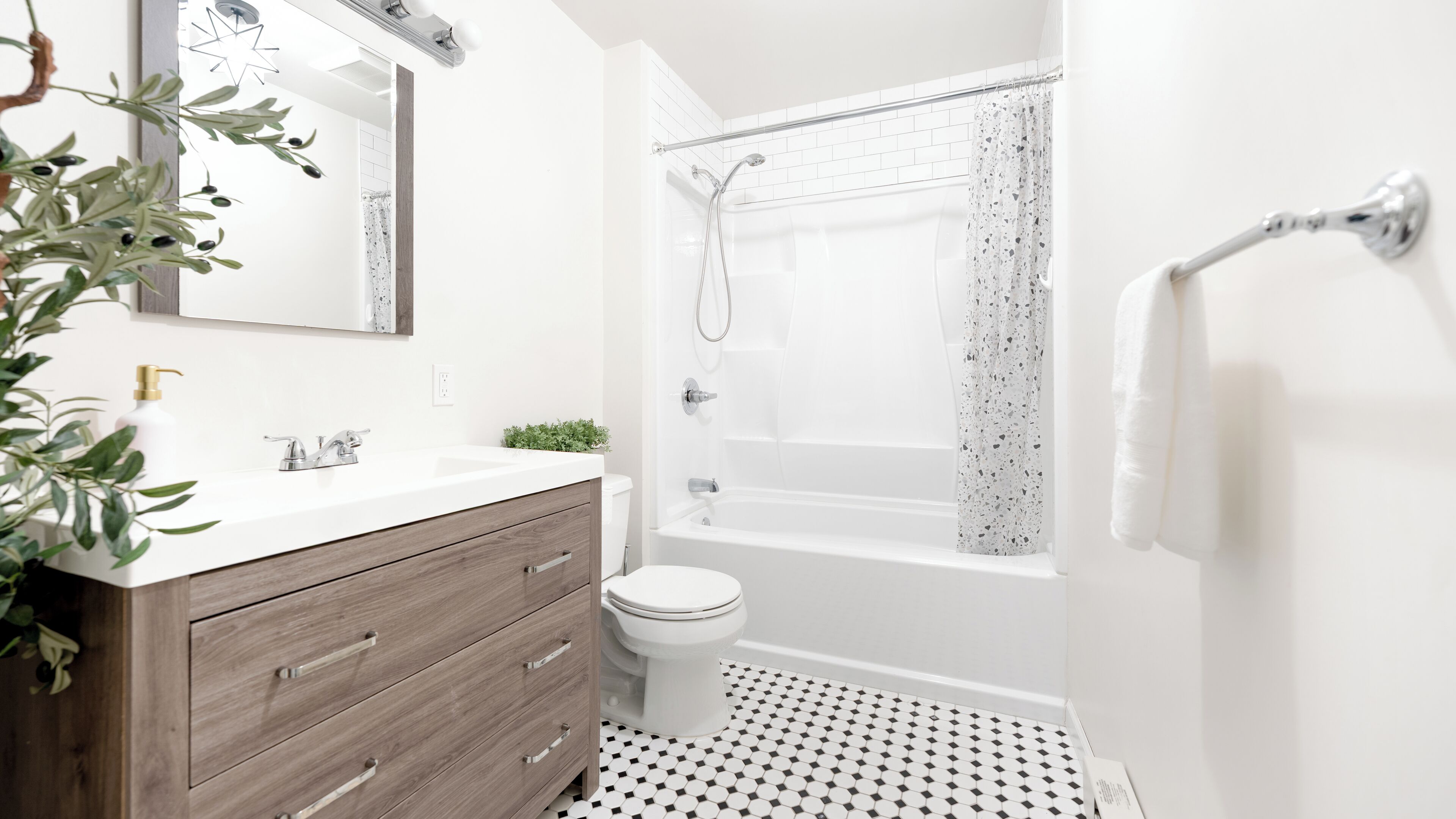 Een moderne badkamer met een wit wastafelmeubel, een toilet, een bad en een douche.
