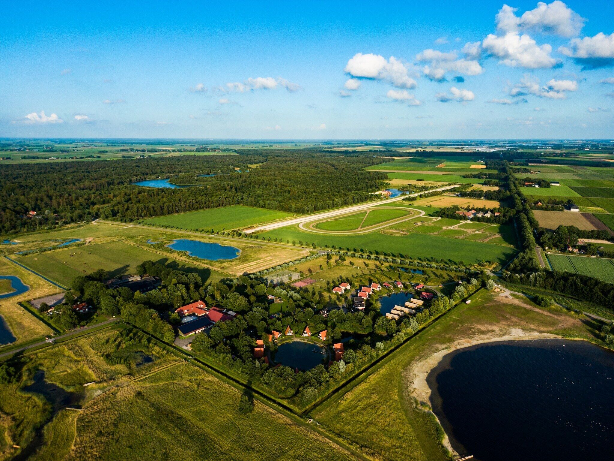 Vista aérea de una zona rural con campos, un lago y un pequeño grupo de casas.