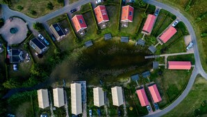 An aerial view of a residential area with houses, a small lake, and a winding road. - Large Countryside Group Stay (Bant)