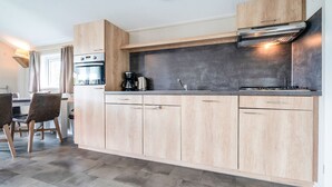 A modern kitchen with wooden cabinets, a built-in oven, and a gas stove.
