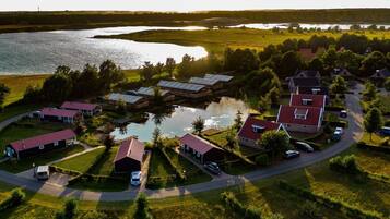 Vue aérienne d’un quartier résidentiel au bord d’un lac, avec des maisons, une jetée et un petit bateau.