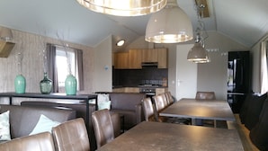 A modern kitchen with wooden cabinets and a built-in oven. There are two dining areas with brown leather chairs and tables. - Pondside Stay w/ Kitchen (Bant)