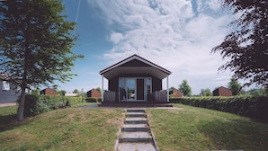A single-story house with a front porch, a clear sky, and a well-maintained lawn. - Pondside Stay w/ Kitchen (Bant)