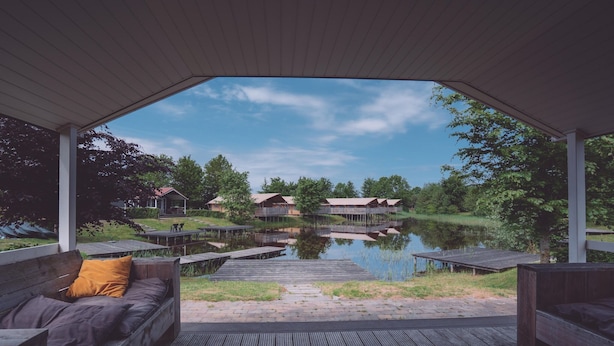 A covered outdoor seating area with a view of a lake and buildings in the distance. - Pondside Stay w/ Kitchen (Bant)
