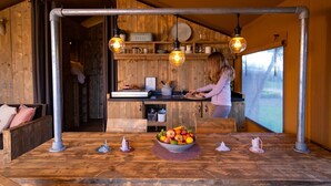 A rustic kitchen with wooden walls, a central island with a fruit bowl, and hanging pendant lights.