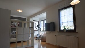 A spacious living room with a large window, a built-in TV, and a ceiling light.