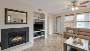 A living room with a fireplace, a television, a ceiling fan, and a sofa. - Single Story Level w/ Heated Pool/Spa/Fitness Rm, Garage, Kierland's Fine Dining/Shopping+FREE GOLF (Scottsdale)