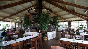 Un restaurant avec un plafond haut, une cheminée en pierre et des tables et des chaises en bois.