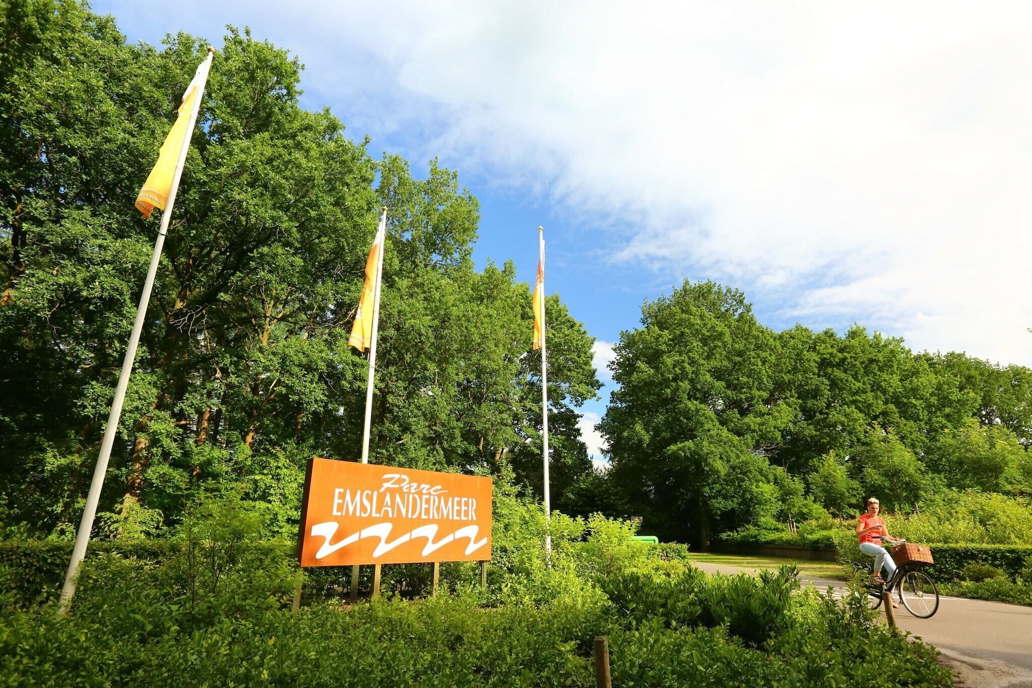 A sign for 'Emslandermeer's' with a cyclist in the background.