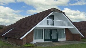 A two-story house with a sloped roof, a balcony, and large sliding glass doors. - Nature Escape w/ Balcony (Vlagtwedde)