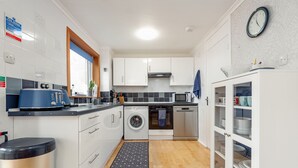 Una cocina moderna con armarios blancos, lavadora, microondas y un fregadero.