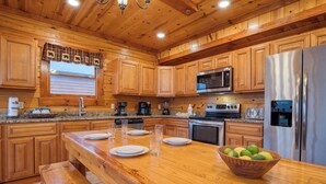 A wooden kitchen with a central island, a refrigerator, a microwave, and a sink. - Sleeps 28 | Indoor Pool, Theater, Game Room, Hot Tub, Views | Marco Polo Lodge (Sevierville)