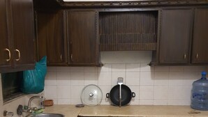 Una cocina con armarios de madera oscura, un lavamanos de acero inoxidable, un dispensador de agua grande y una olla sobre la encimera.