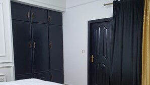 Un dormitorio con cama, armario, puerta y cortina.