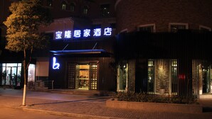 Ein Hotel mit Eingang, einer Neonreklame, einer Ziegelwand und einem abschließbaren Tor.