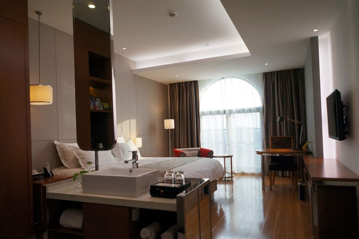 Een moderne hotelkamer met een groot bed, nachtkastje en een bureau.