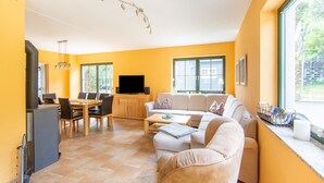 A modern living room with a sofa, dining table, and TV. - Pet-Friendly Getaway (Eisfeld)