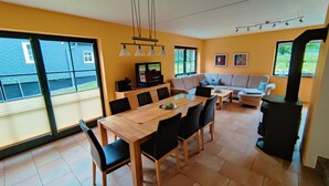 A modern living room with a wooden dining table, black chairs, a sofa, and a television. - Pet-Friendly Getaway (Eisfeld)
