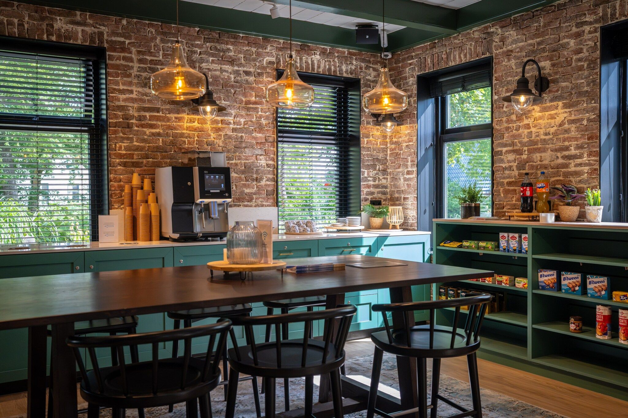 A restaurant interior with a brick wall, hanging pendant lights, a coffee machine, and a counter with stools.