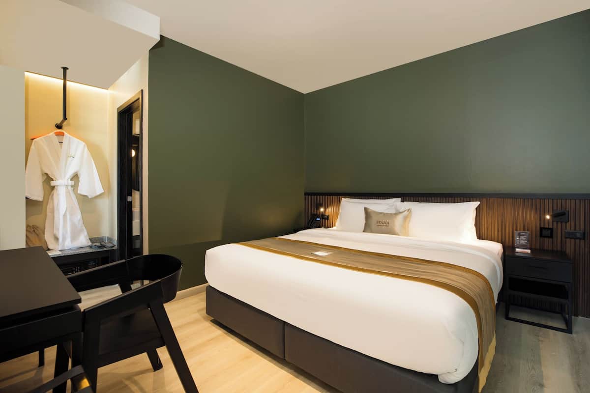 A modern hotel room with a large bed, a desk, and a chair.