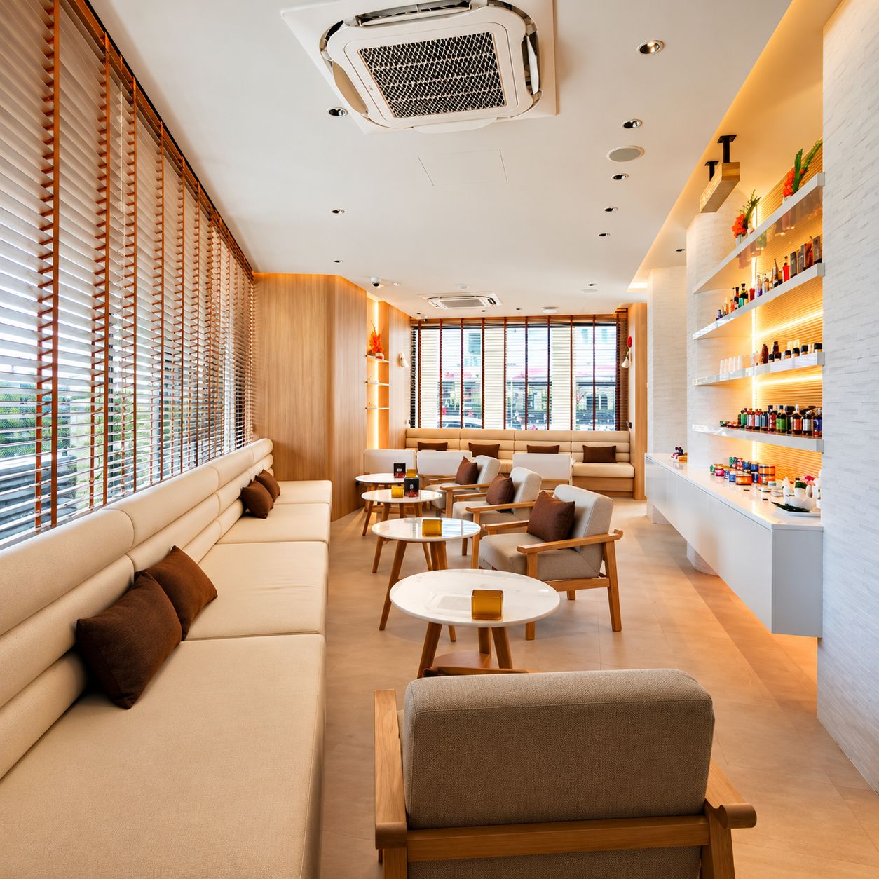 A modern interior with a sofa, chairs, tables, and a shelf with bottles.