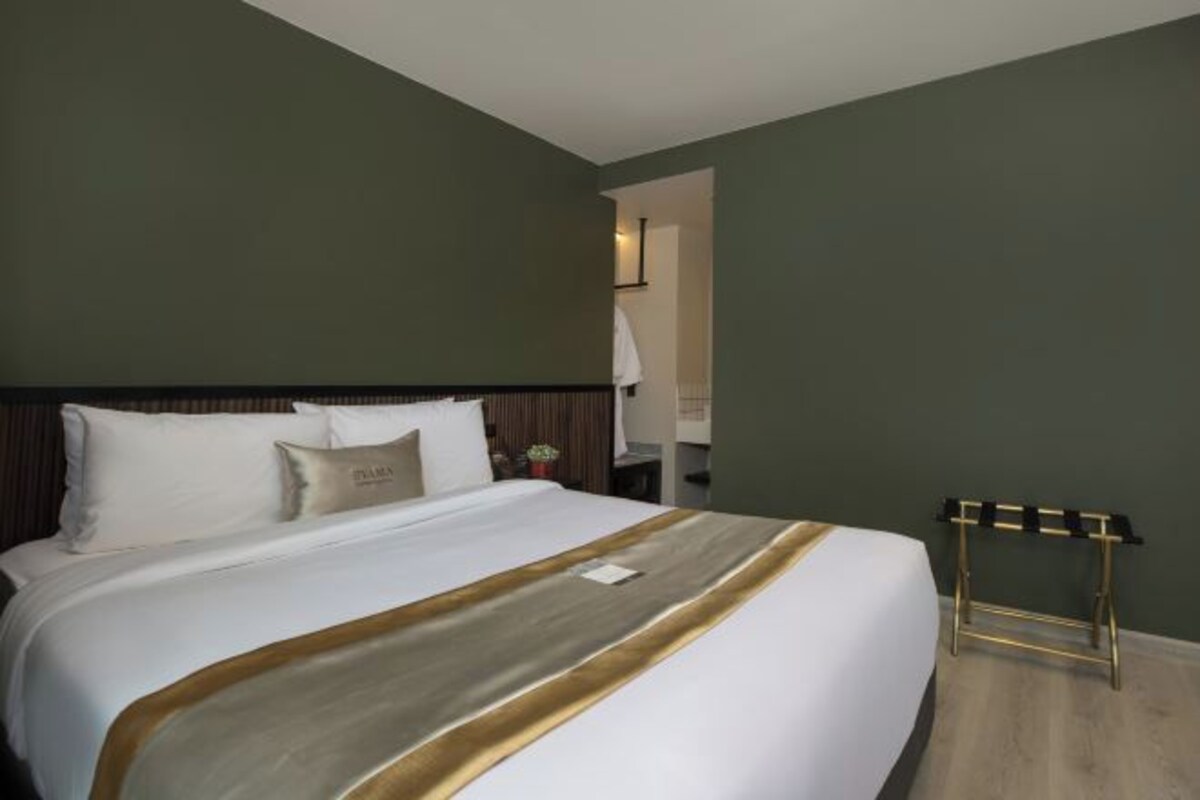 A hotel room with a large bed, a bedside table, and a small table with a tray.