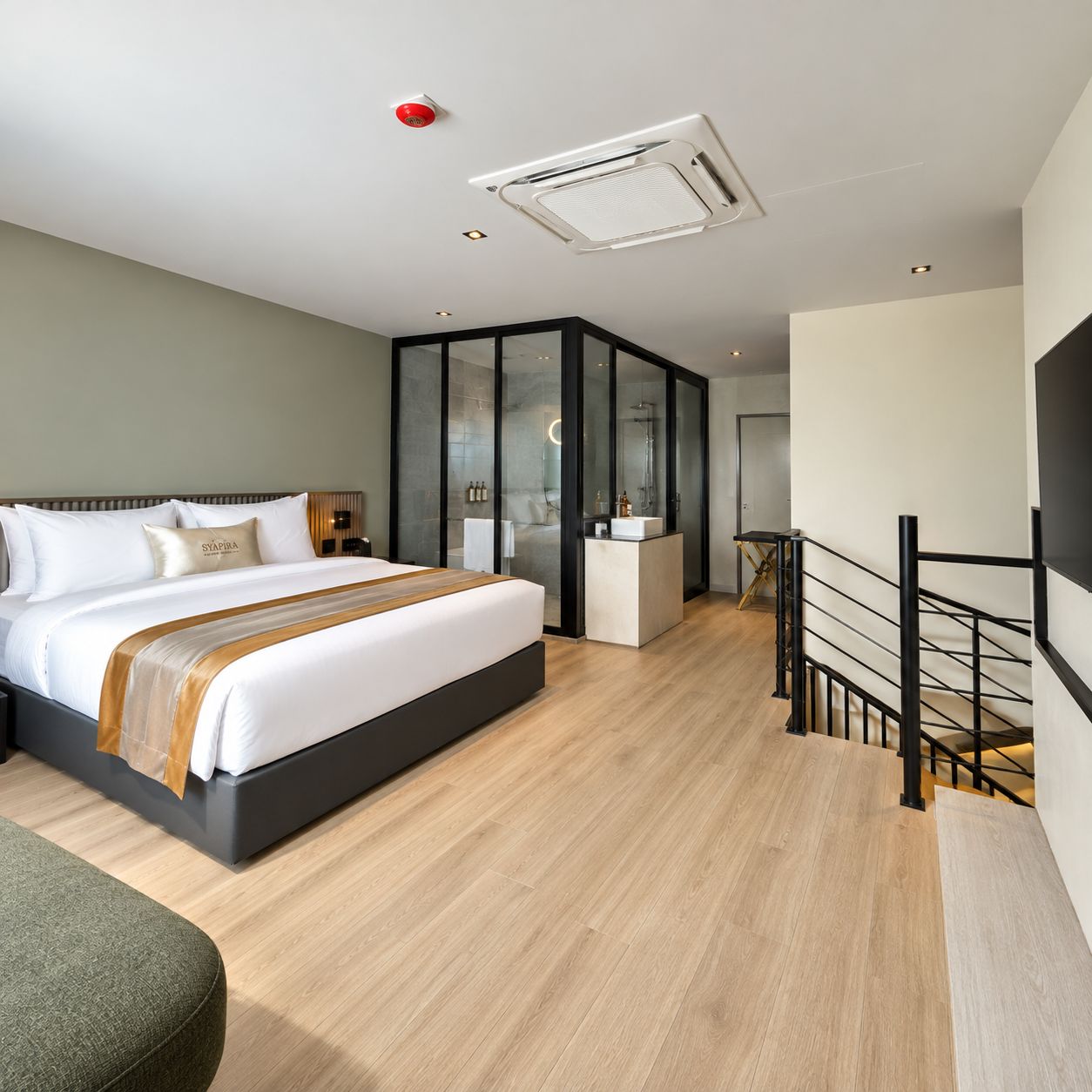 A modern hotel room with a large bed, a glass-enclosed bathroom, and a staircase.