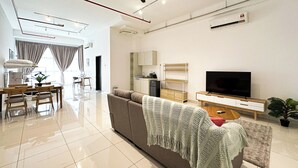 A modern living room with a sofa, TV, and dining area. - 3 Towers Jln Ampang by Airhost (Kuala Lumpur)