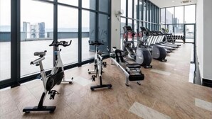A gym with various exercise equipment, large windows, and a view of buildings. - 3 Towers Jln Ampang by Airhost (Kuala Lumpur)