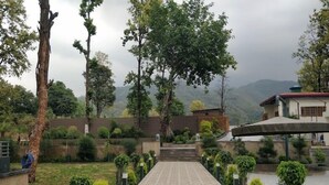 A paved pathway leading to a building with a view of mountains. - The Green Icon Resort (Rishikesh)
