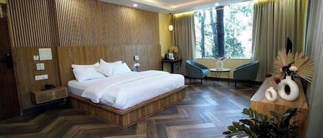 Habitación de hotel moderna con cabecera de madera, una cama grande, un escritorio, una silla y una planta en maceta.