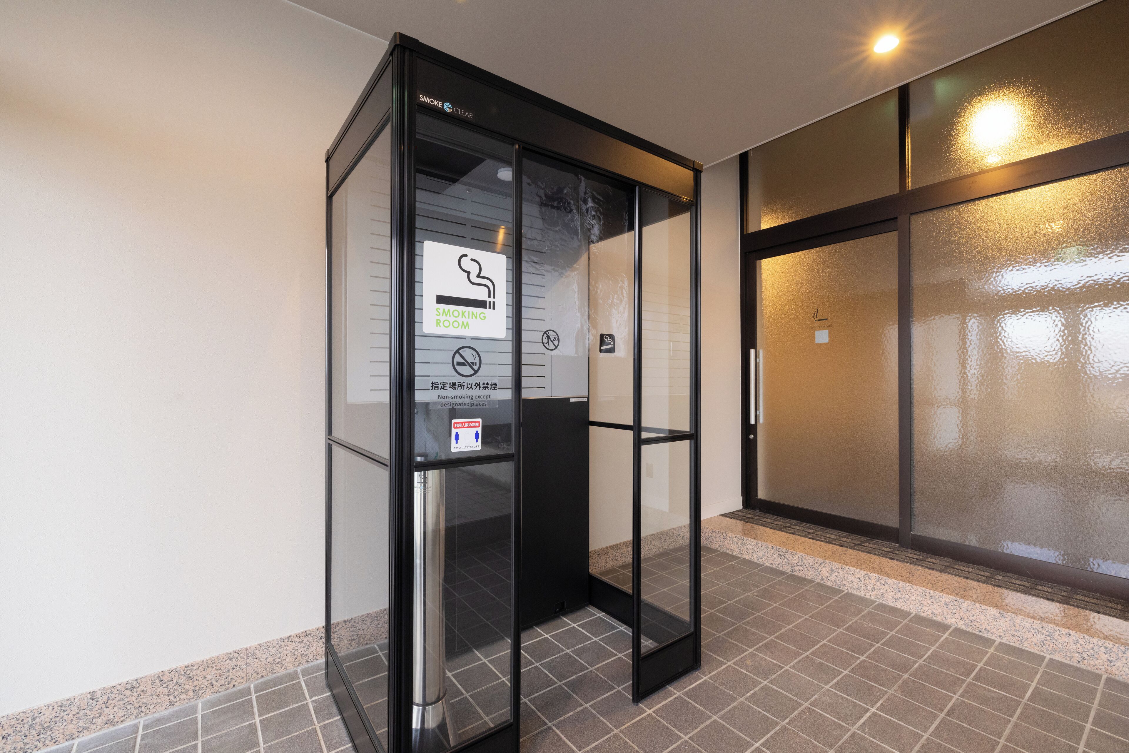 Habitación para fumadores con puertas de cristal y un cartel que indica que no se permite fumar.