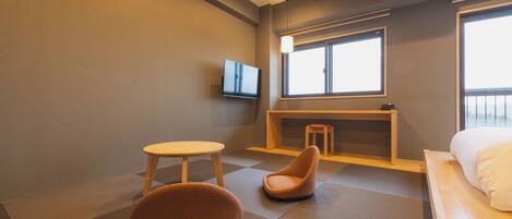 Een moderne hotelkamer met een bed, een televisie, een tafeltje en een stoel.