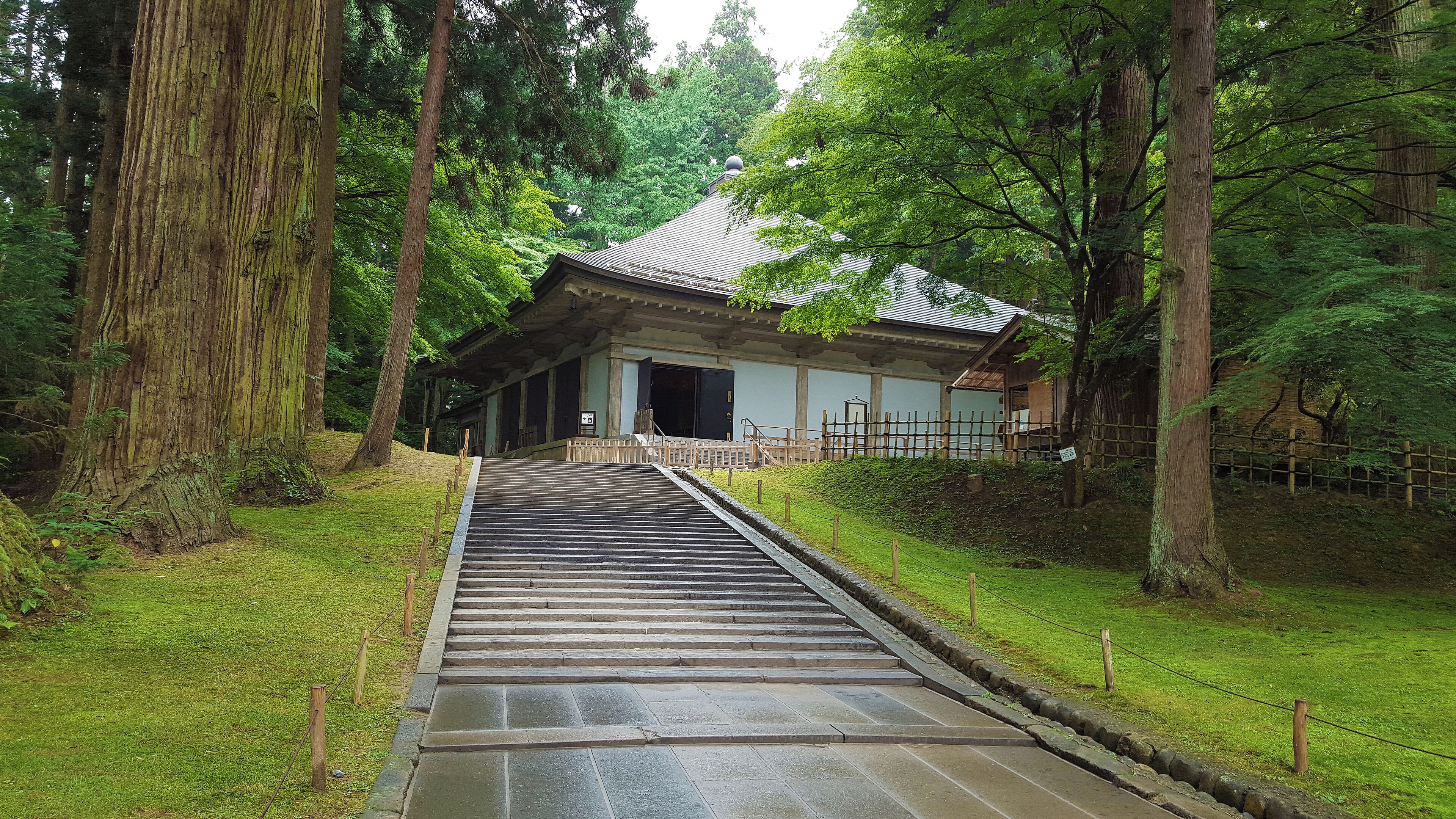 Un edificio japonés tradicional con una escalera de madera que conduce a una entrada con tejas.
