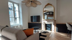 En moderne stue med sofa, TV, pejs og et stort spejl.