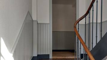 A staircase with wooden steps and a metal railing, leading to a landing with a white door and a window above.