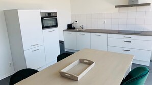 A modern kitchen with white cabinets, a built-in oven, a sink, and a wooden table with a tray. - Trompstraat (Eindhoven)