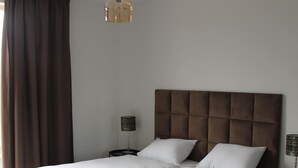 A double bed with a tufted headboard, two bedside tables with lamps, and a hanging light fixture. - Trompstraat (Eindhoven)
