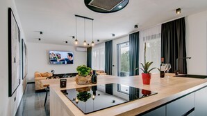 Una cocina moderna con una isla central, un área de comedor con sofá y un televisor en la pared.