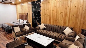 A cozy room with wooden walls, a ceiling fan, a sofa set, and a coffee table. - Classic Hills Villa Mussoorie (Mussoorie)